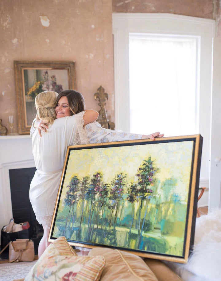 Katie Jacobson Hugging Client while Delivering a Landscape Painting